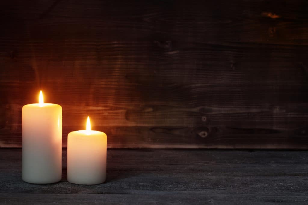 Burning candle on old dark wooden background